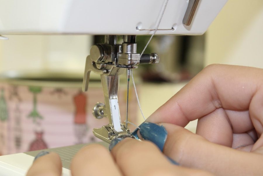 Photo of a fashion student using a sewing machine to work on her designs.