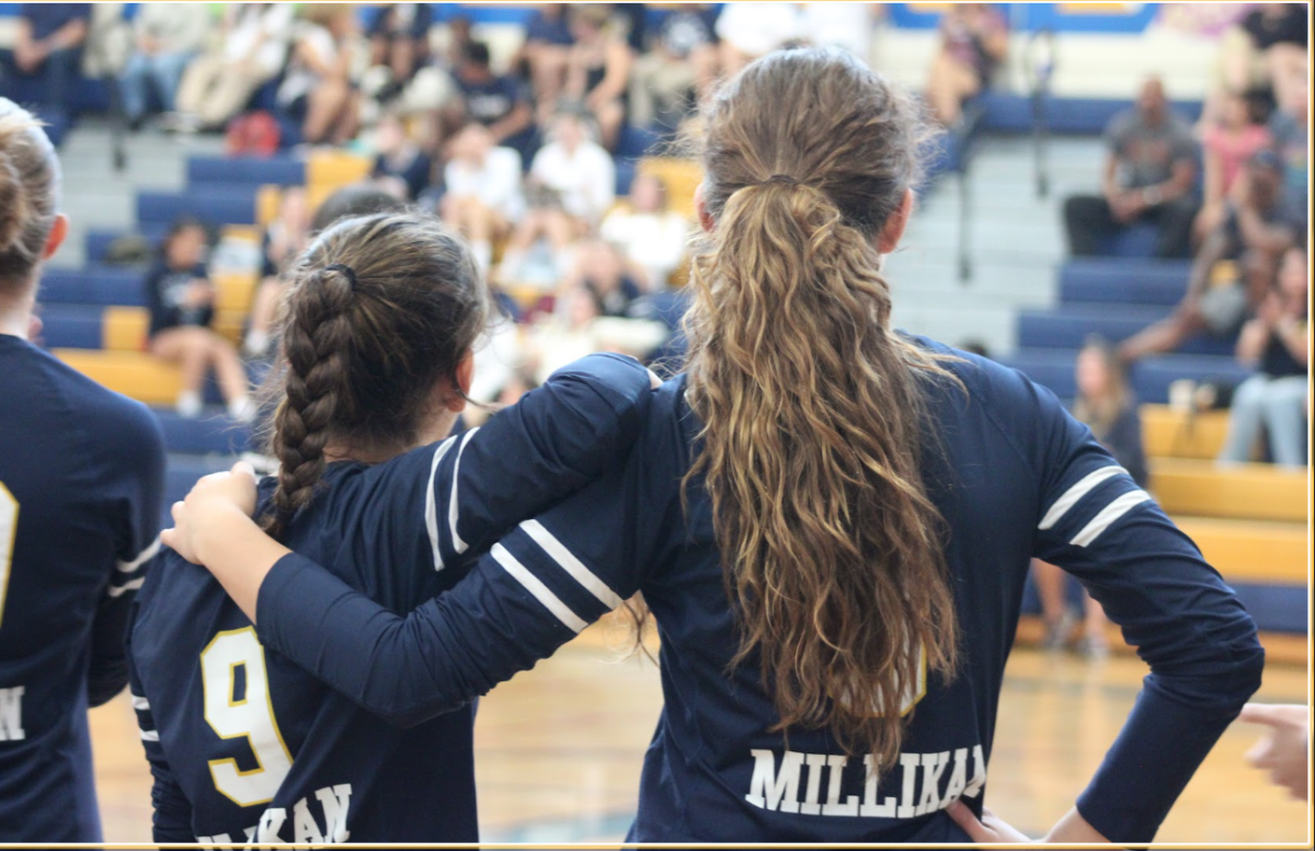 The picture above depicts two Millikan Volleyball girls watching the game from the sidelines.