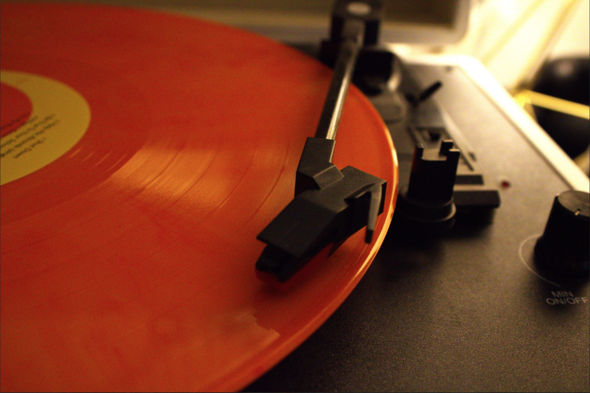 Photo of an orange vinyl record playing on a record player.