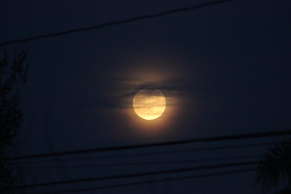 Photo of the moon partially covered by a cloud.