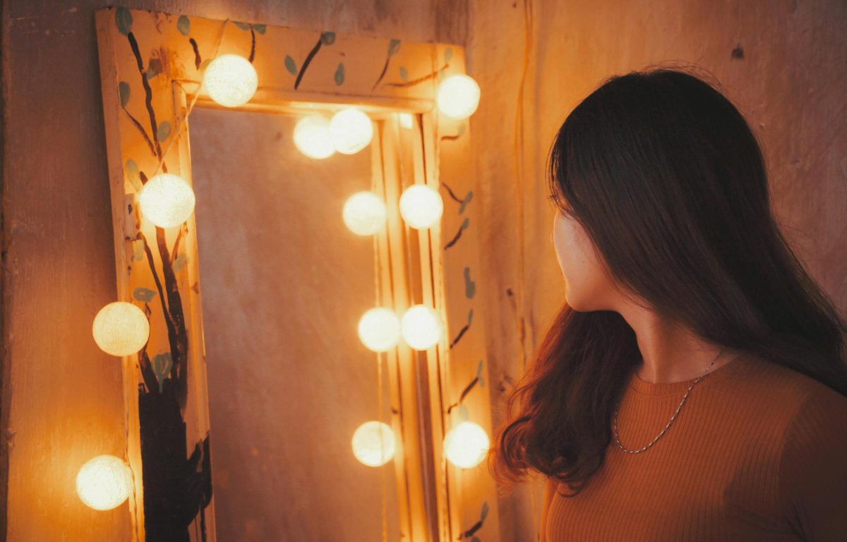 Photo of woman looking into mirror (Photo Courtesy of Pexels.com)