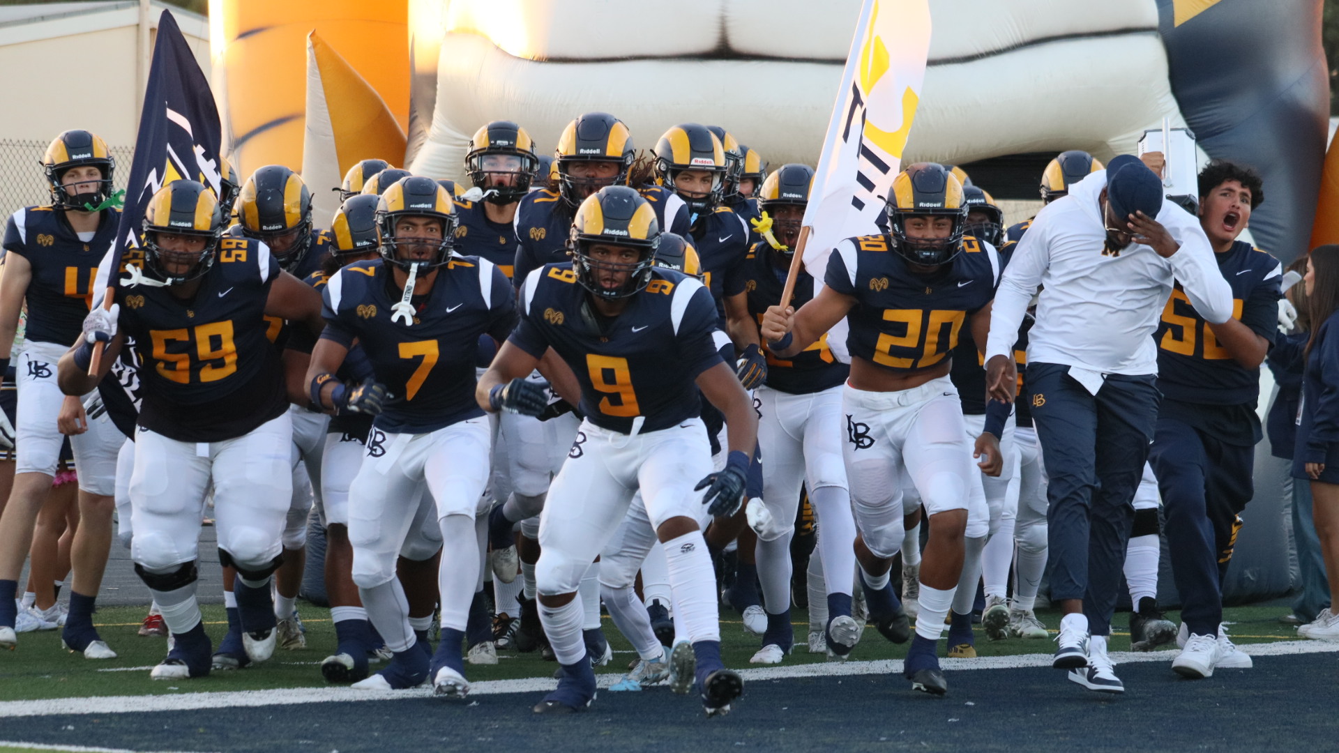 Photo of Millikan Football running on to the field. 