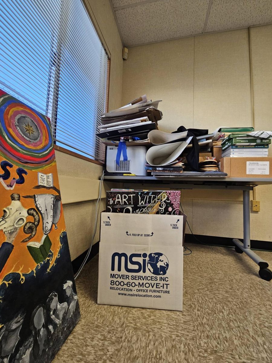 Photo of boxes, posters, and other items being packed up inside a classroom.