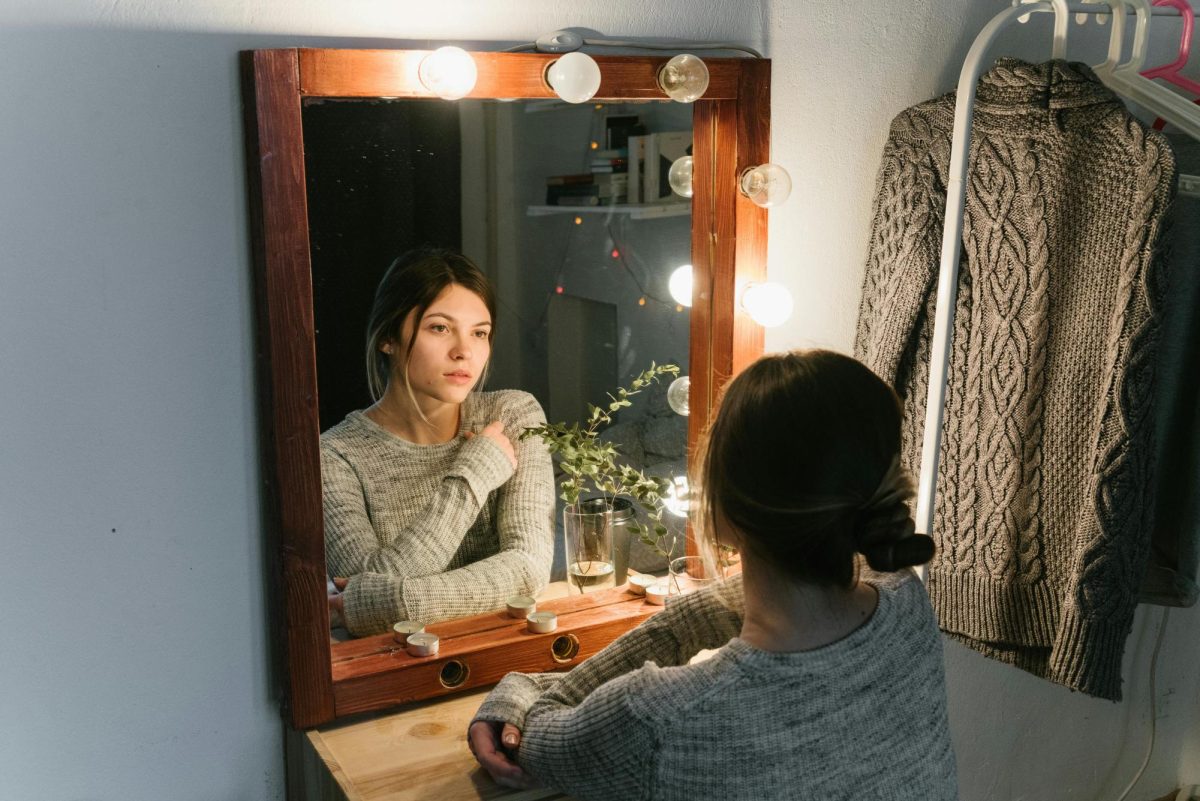 Photo of woman looking into her reflection. (Photo courtesy of pexels.com)